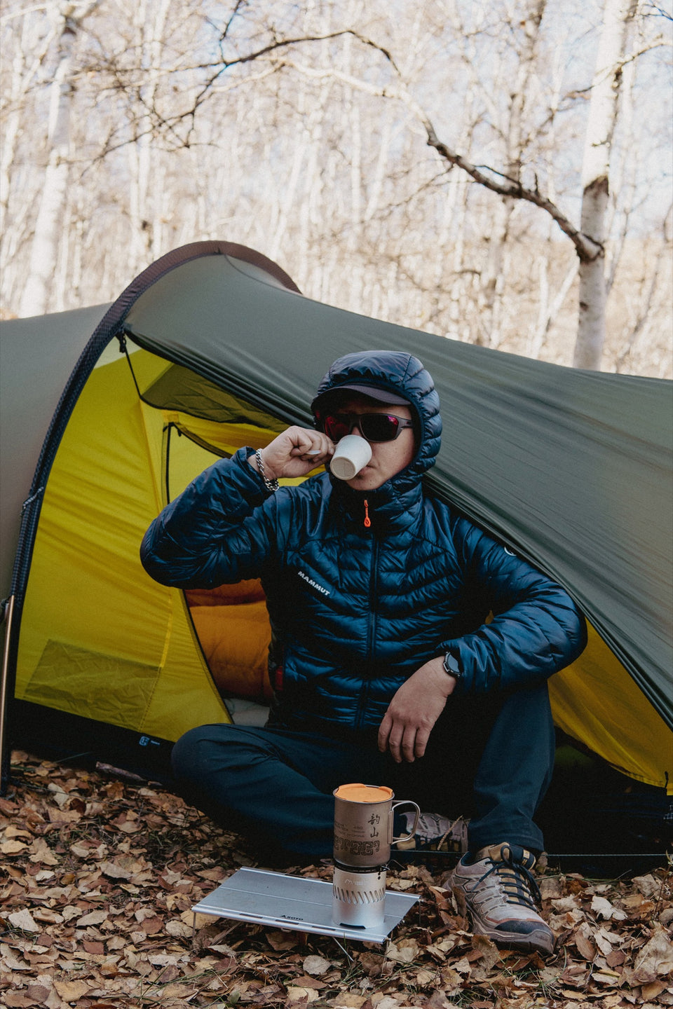 Hiker drinking beside a tent after using the Blaze stove