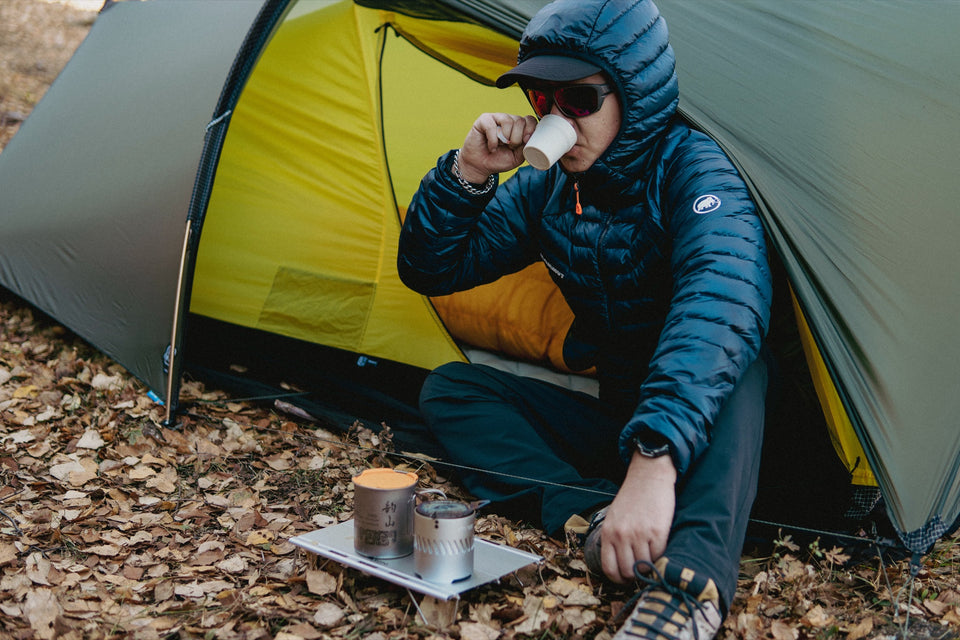 Solo hiker using the Blaze alcohol stove beside a trekking tent