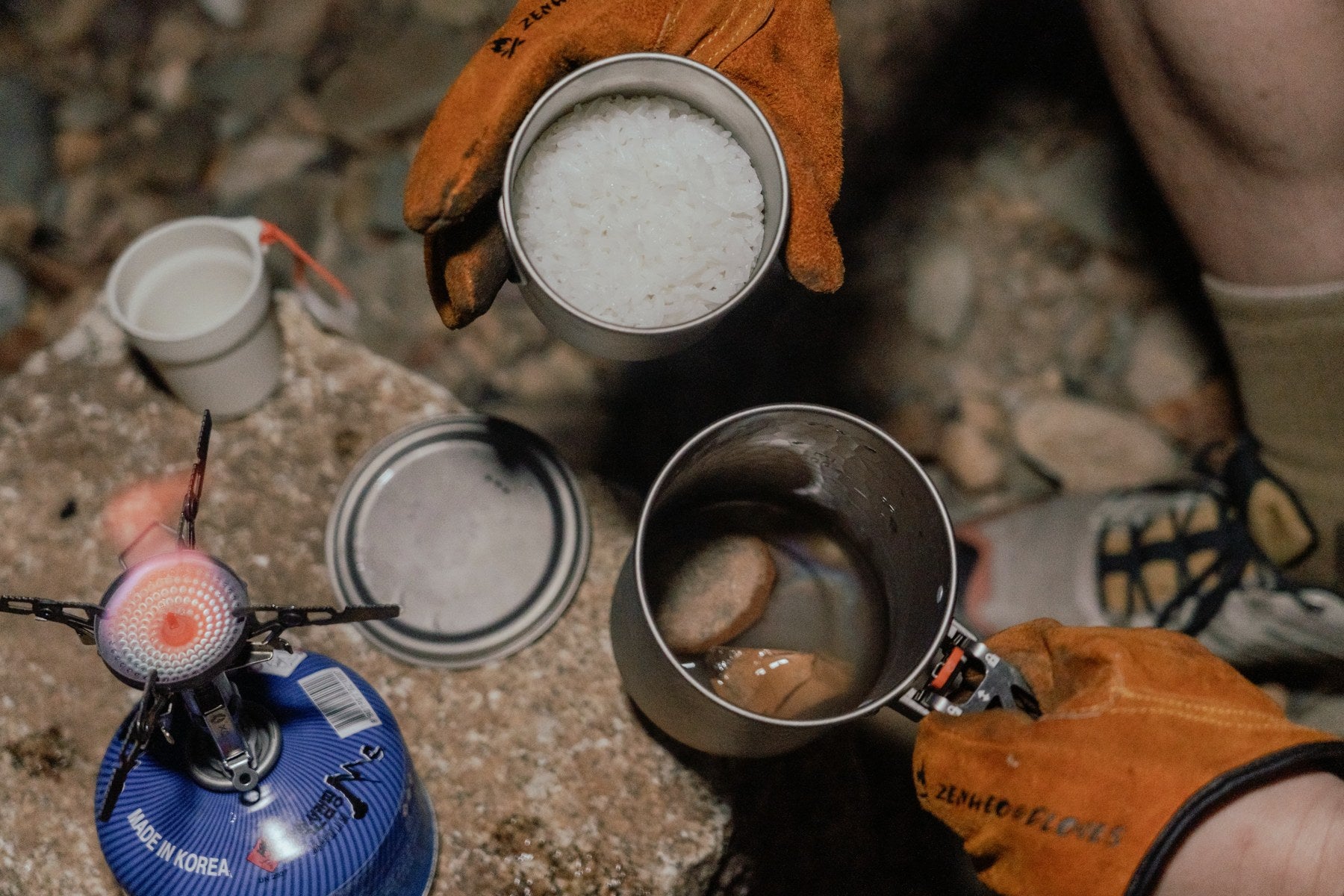 Preparing a meal with a pot and bowl beside a separate gas stove